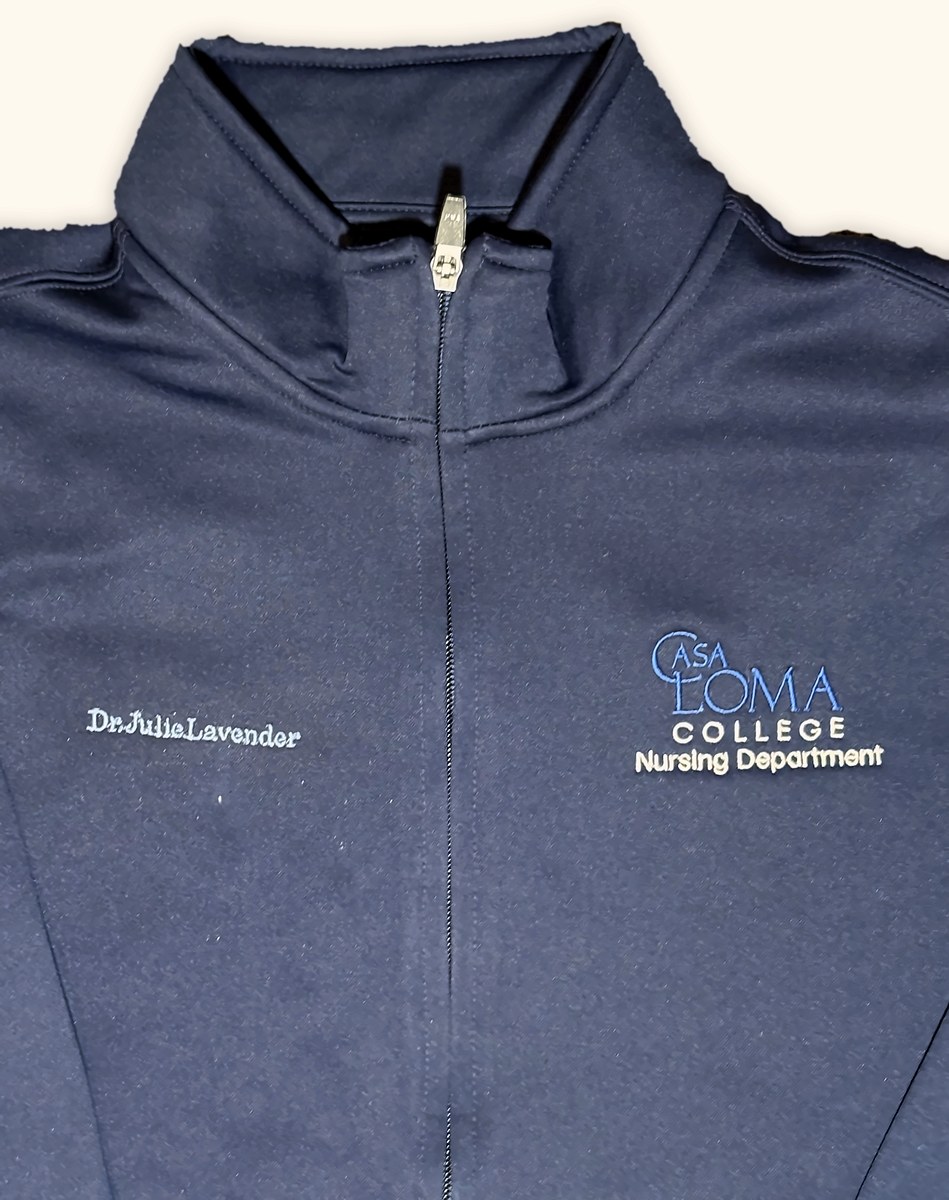 Navy zip jacket embroidered with a name and a college nursing department logo